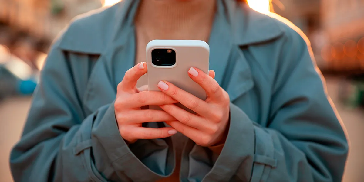Persona utilizando un iPhone para buscar una aplicación mediante Spotlight y otras herramientas de iOS.